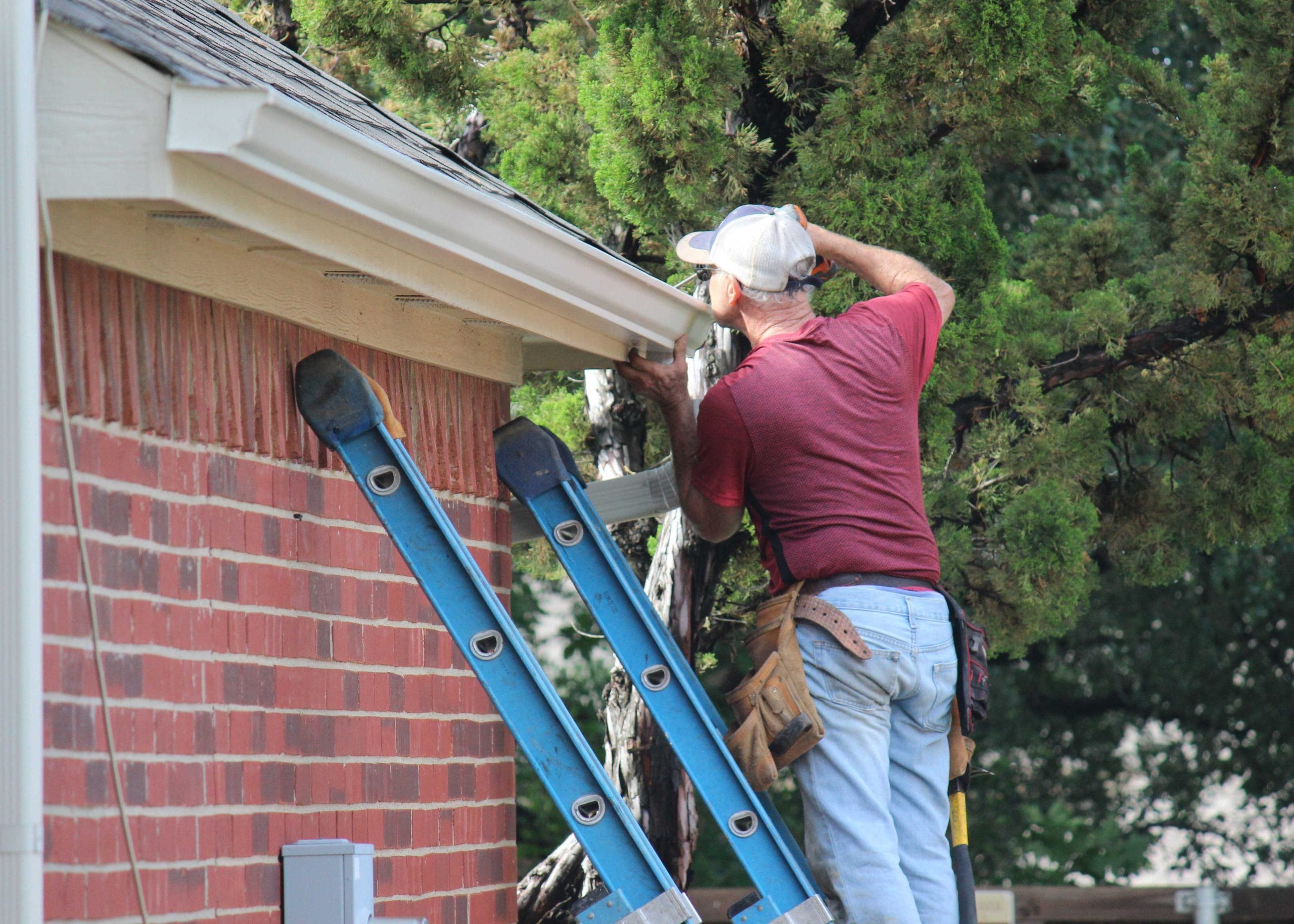 A roofing replacement expert on industrial ladder fixing gutters in Hot Springs, Arkansas